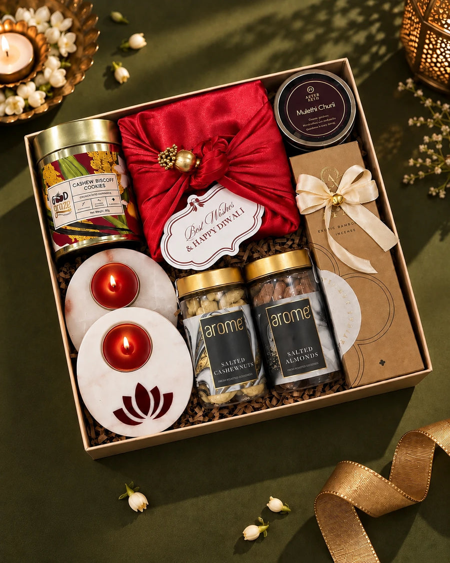 Open cream box seen from above, marble tealight diyas lit beside salted nut jars and a cookie tin — Veda Diwali gift hamper