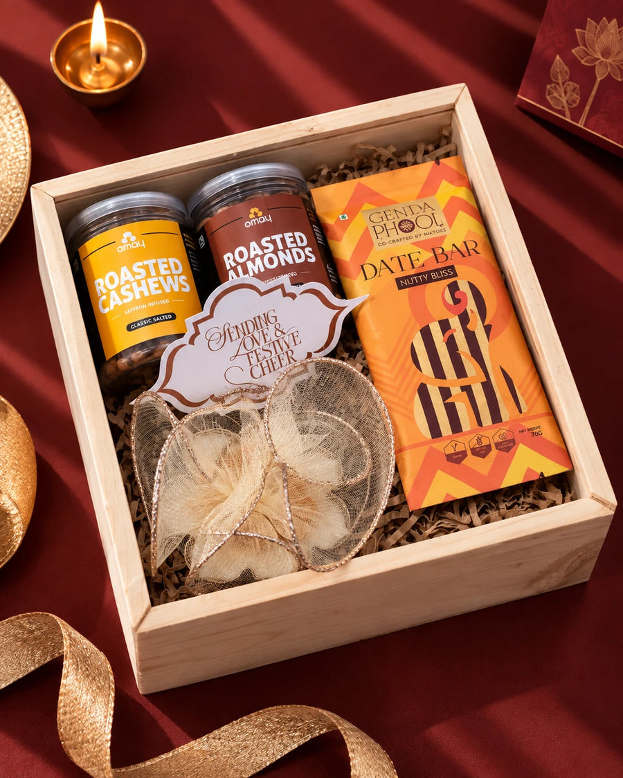 Open pinewood box with saffron cashew and almond jars, a date bar and a gold-net wrapped candle — Aakar Diwali gift hamper